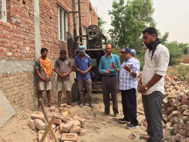 Pastor Singh (bright blue shirt), Pastor Koshy and workers pray at the beginning of another work day on the new building.